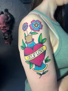 Tatuagem colorida com flores no braço — trabalho de Thaís Muniz